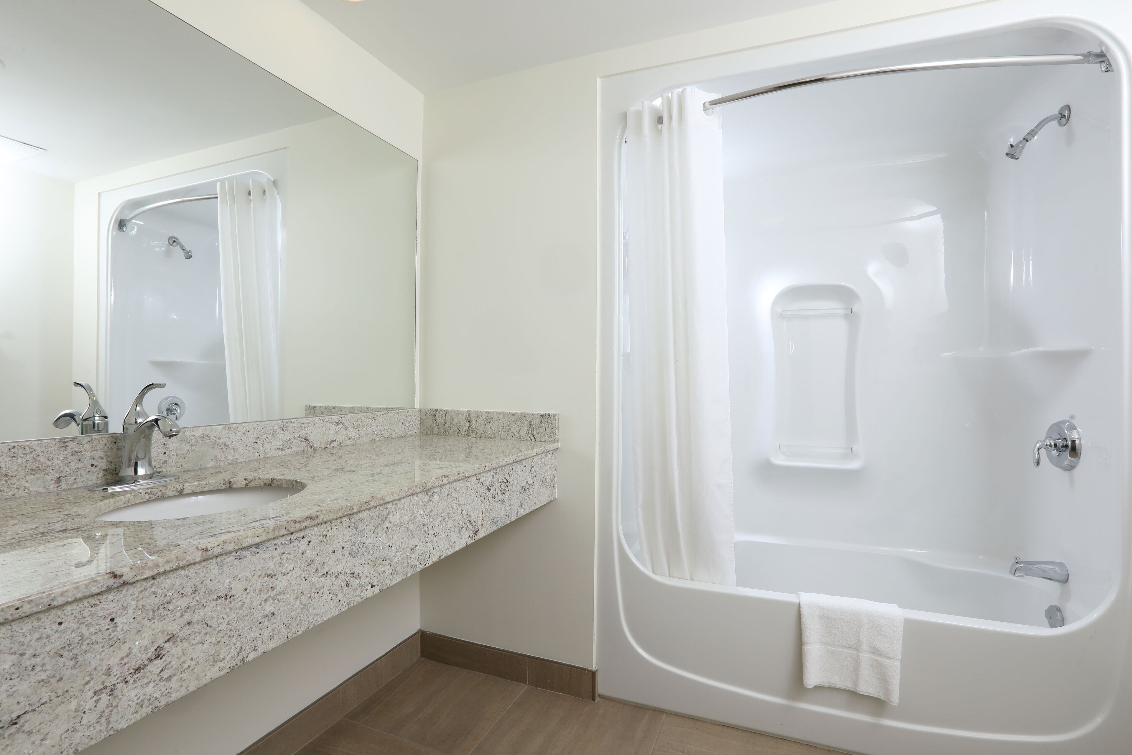 A bathroom with a sink, mirror, and a bathtub.