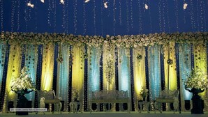Un escenario decorado con arreglos florales e iluminación colgante.
