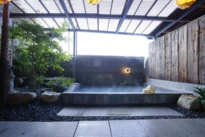 A traditional Japanese-style hot spring bath area with stone steps, a wooden wall, and a stone bench. - Hotel Kikunoya (Hatsukaichi)