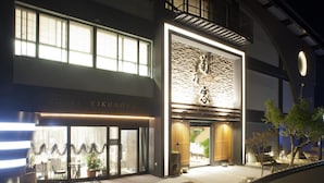 A hotel with a modern facade, large windows, and a well-lit entrance area. - Hotel Kikunoya (Hatsukaichi)