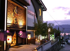 A traditional Japanese building with a stone wall facade, wooden beams, and a large circular window. - Hotel Kikunoya (Hatsukaichi)