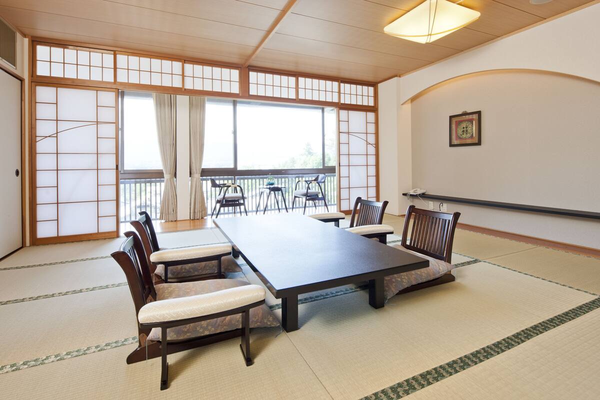 A traditional Japanese-style meeting room with tatami flooring, a low table, and wooden chairs.