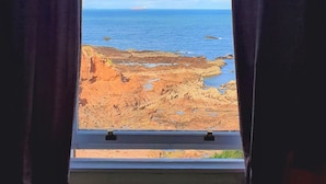 A window with a view of a rocky shoreline and the ocean. - Bayswell Park Hotel (Dunbar)