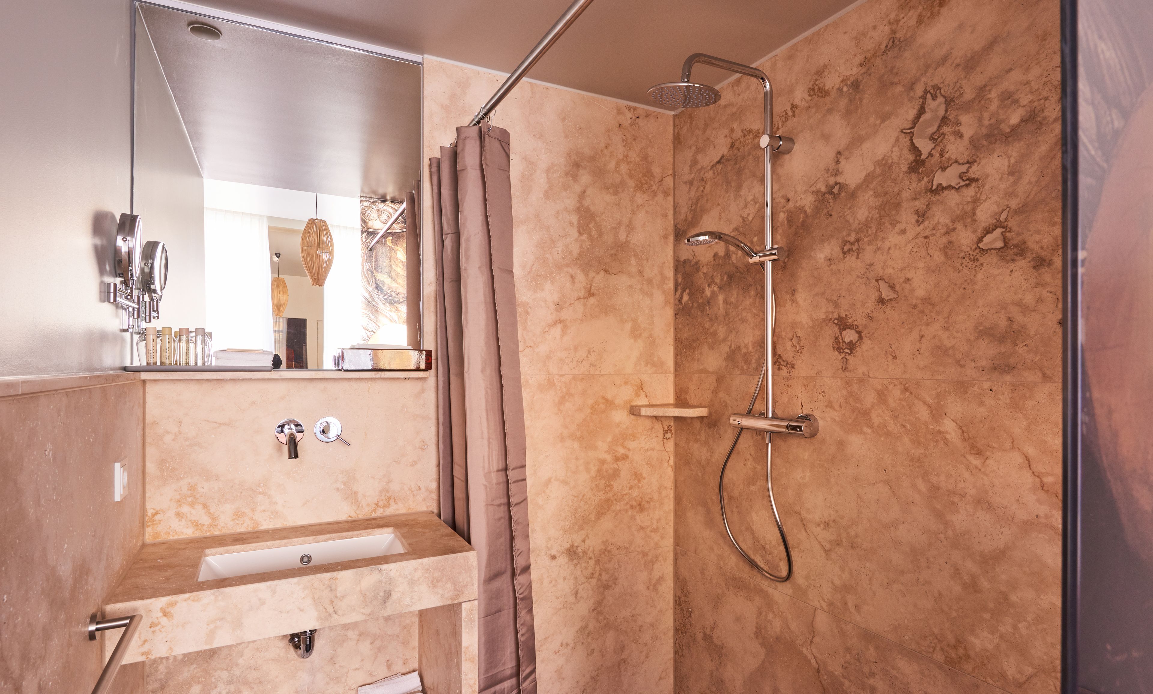 A bathroom with a sink, mirror, shower, and towel rack.