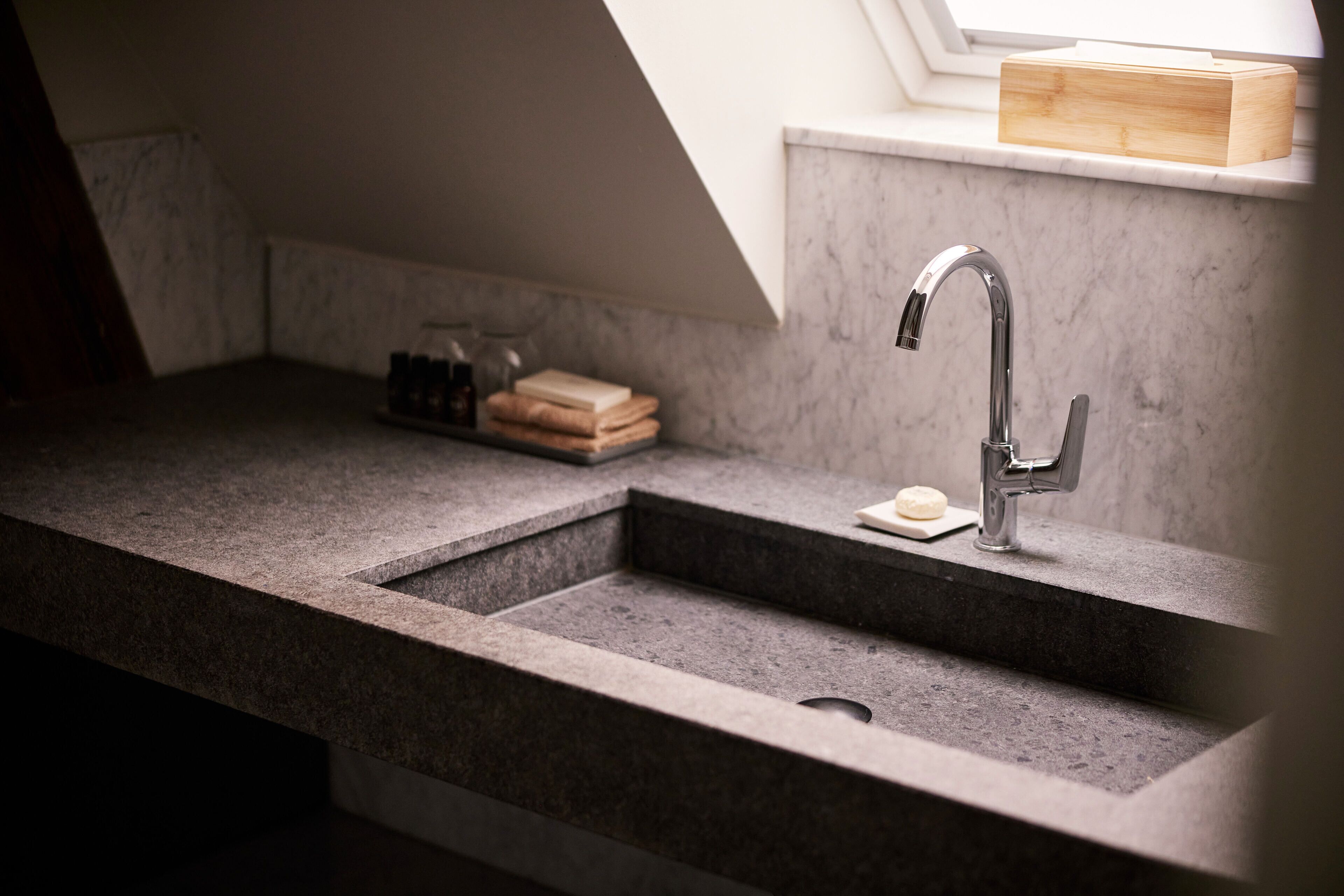 A modern kitchen with a granite countertop, a stainless steel sink, and a window above the sink.
