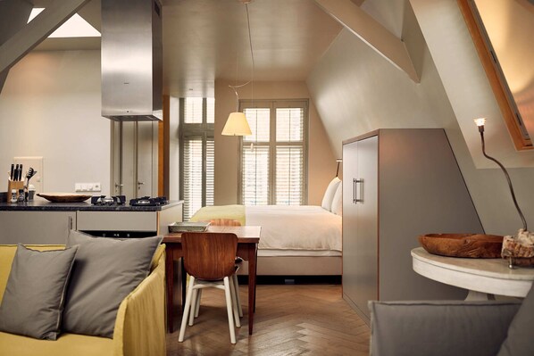 Habitación de hotel compacta con kitchenette, cama, zona de comedor y baño.