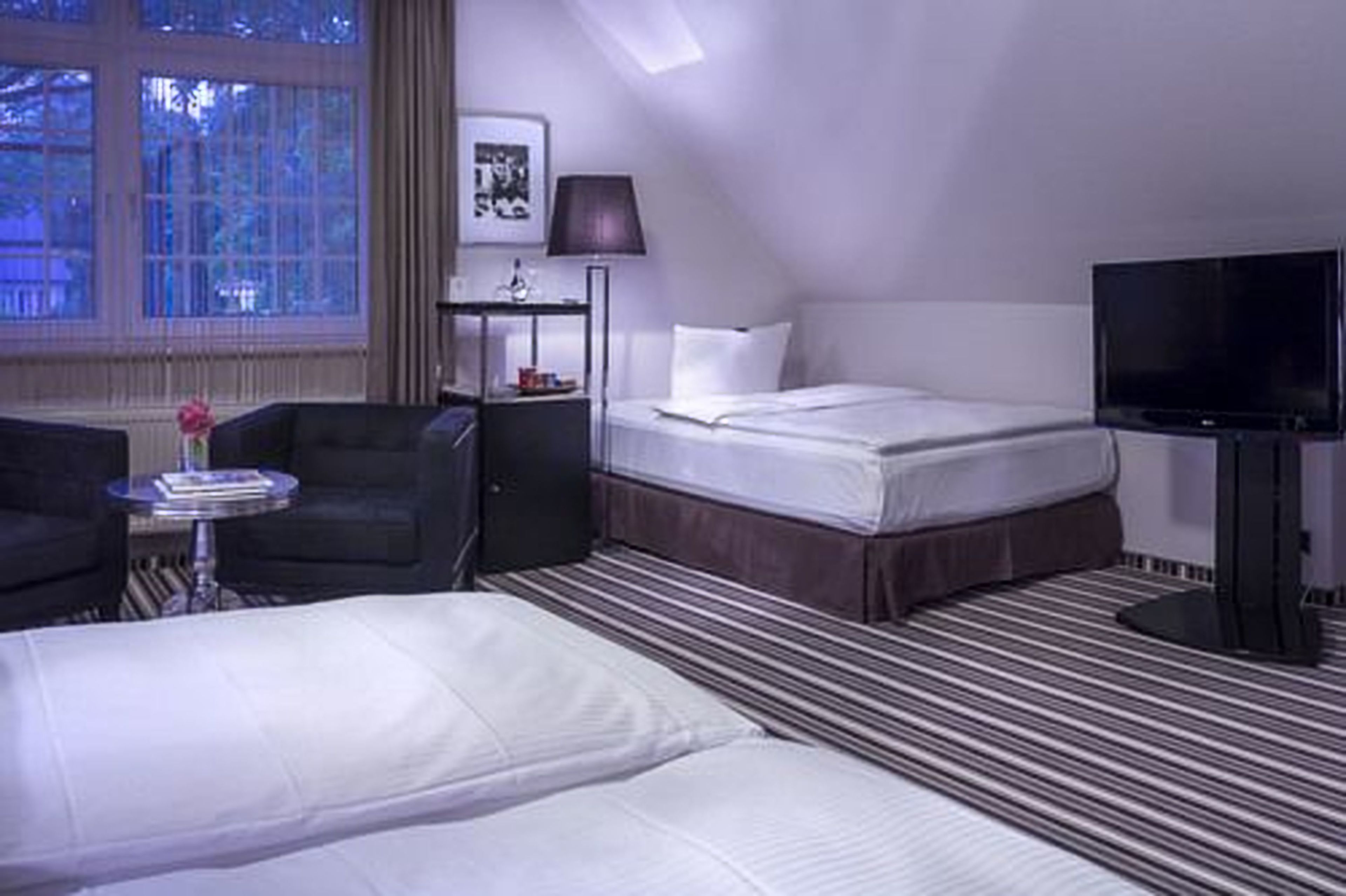 Una habitación de hotel con cama, televisión, escritorio y silla.