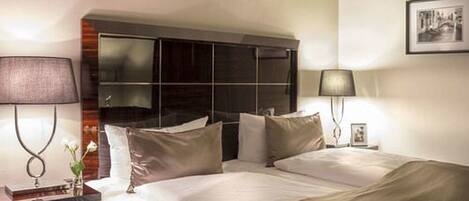 Una habitación de hotel con una cama grande, dos mesitas de noche y una lámpara de pared.