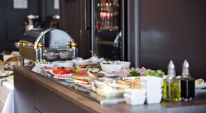 A buffet with various food items and a grill in the background. - Boutique Hotel Poppenbütteler Hof (Hamburg)