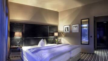 Une chambre d’hôtel avec un grand lit, deux tables de chevet, une tête de lit et une vue sur l’extérieur.