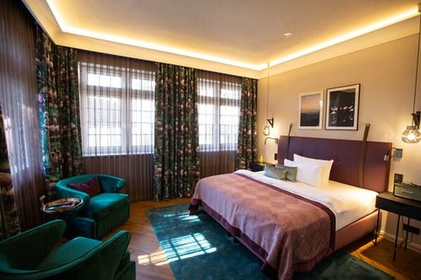 A hotel room with a large bed, two chairs, a nightstand, and a window with curtains. - Boutique Hotel Poppenbütteler Hof (Hamburg)