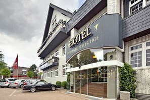 A hotel with a prominent sign, a parking lot with cars, and a clear sky. - Boutique Hotel Poppenbütteler Hof (Hamburg)