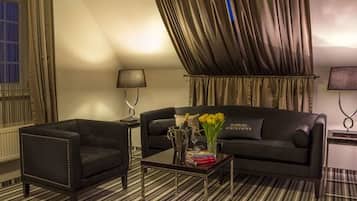 Ein modernes Wohnzimmer mit einer schwarzen Couch, einem schwarzen Sessel und einem Couchtisch mit Büchern und einer Blumenvase.