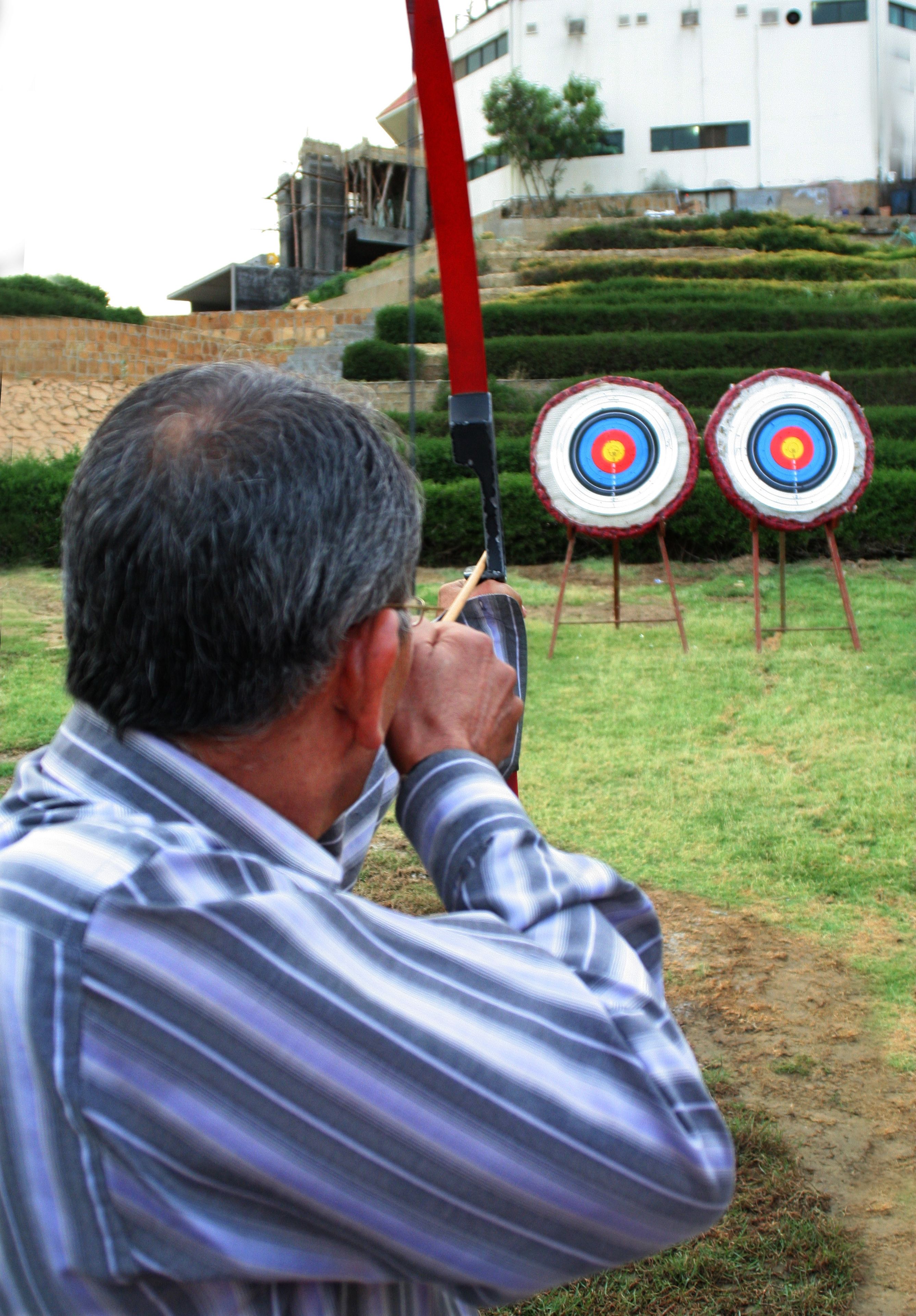 A man aiming at two archery targets in an outdoor setting.