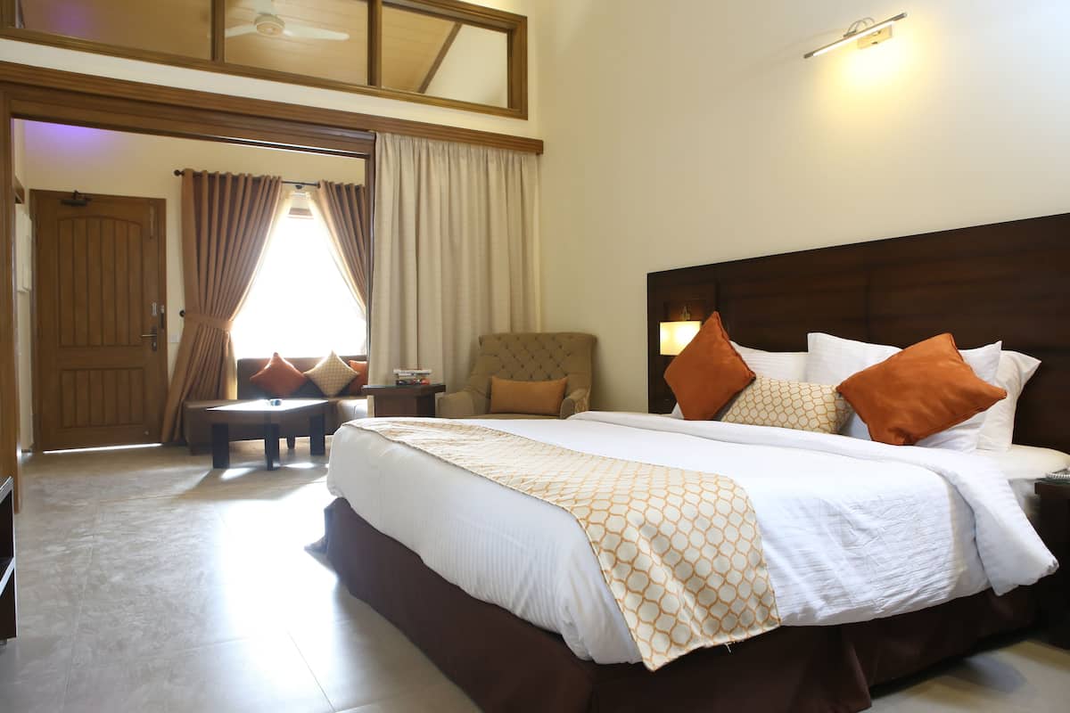 A hotel room with a large bed, a chair, a table, and a view of the outside.