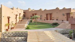 A courtyard with a central staircase, surrounded by buildings with flat roofs and potted plants. - Dreamworld Resort, Hotel & Golf Course (Karachi)
