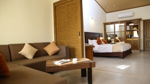 A hotel room with a sofa, a wooden coffee table, a bed with pillows, and a wardrobe. - Dreamworld Resort, Hotel & Golf Course (Karachi)