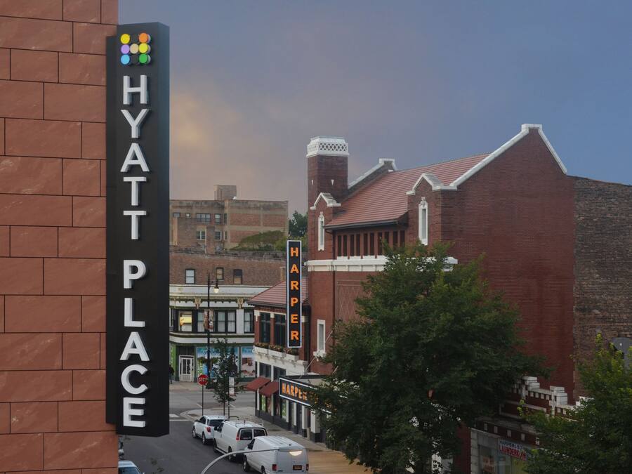 A street view with a brick building labeled "HYATT PLACE" and a sign for "HARPER'S LAUNDRY."