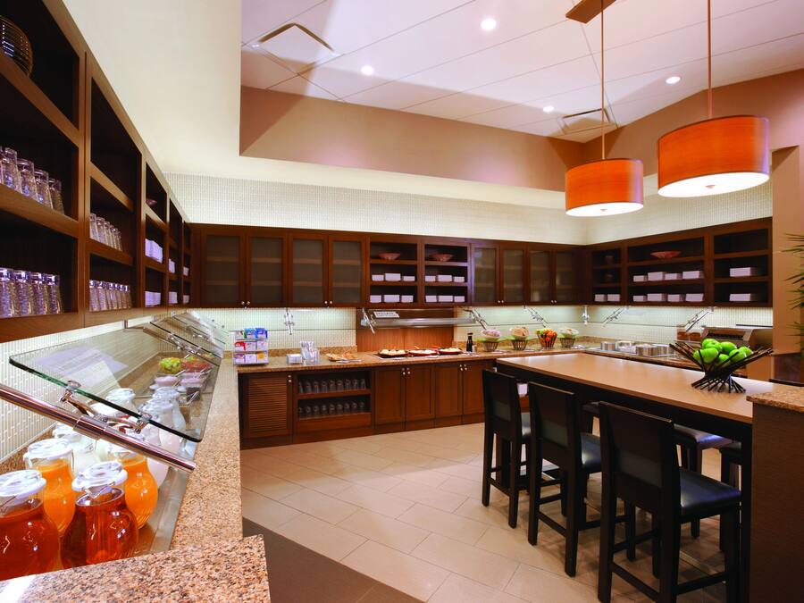 A modern kitchen with granite countertops, wooden cabinets, and a central island with bar stools.