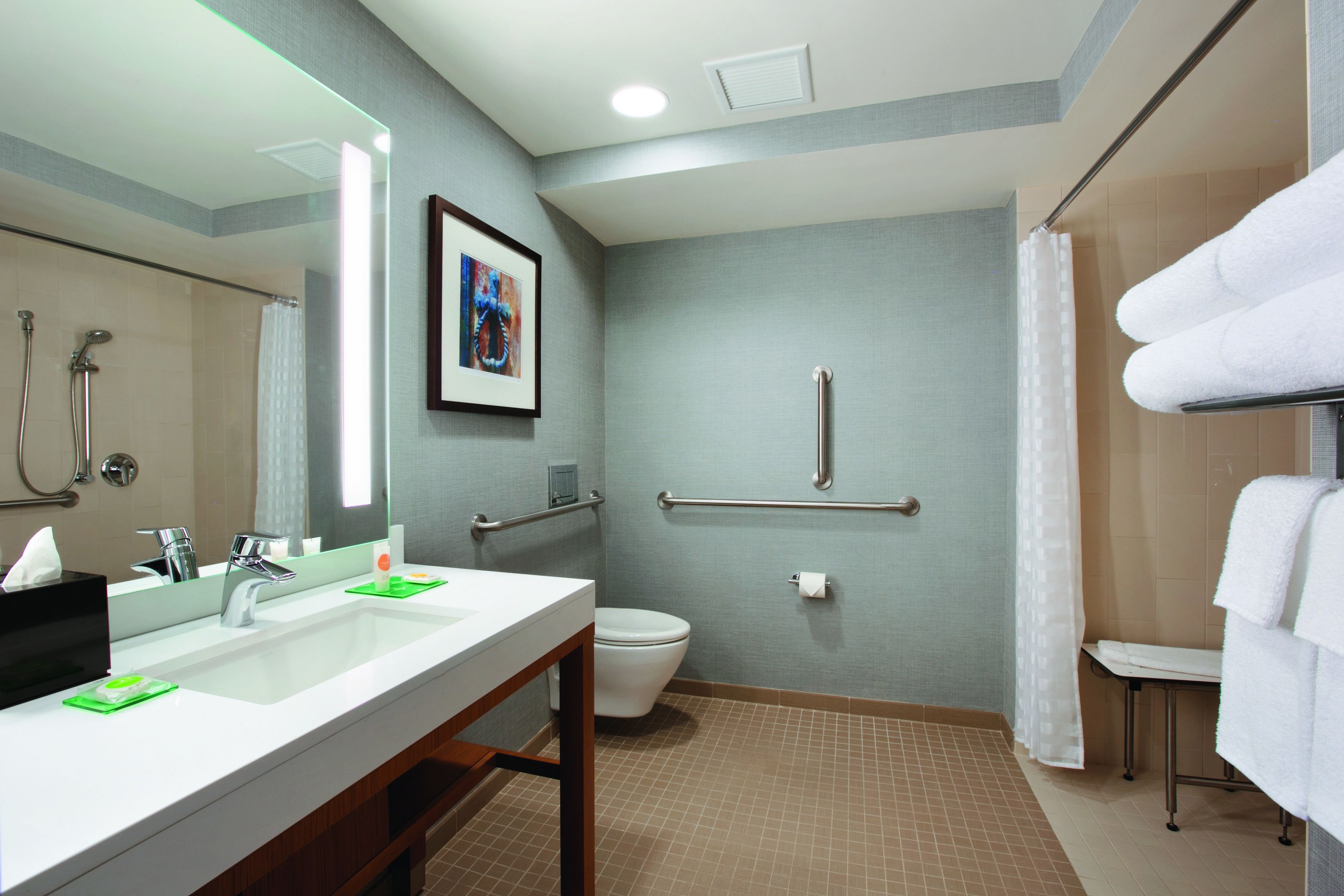 A modern bathroom with a large mirror, two sinks, a toilet, a shower area, and a towel rack.