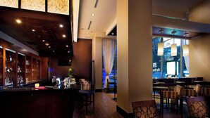 A bar area with a wooden counter, seating, and a view of the city through a window.
