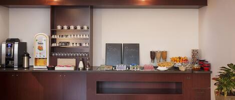 A reception area with a coffee machine, a fruit display, and a chalkboard with writing.