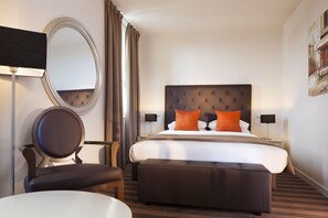 Een hotelkamer met een groot bed, een ronde spiegel, een stoel en een klein tafeltje.