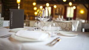 Une table de restaurant dressée avec des assiettes, des couverts et un présentoir à menus.