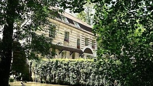 Un bâtiment historique doté d’une façade en pierre, de fenêtres en arc de cercle et d’une conception symétrique.