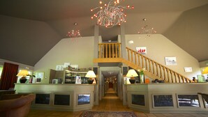 Un hall d’entrée spacieux avec un plafond haut, un escalier central et un espace bar.