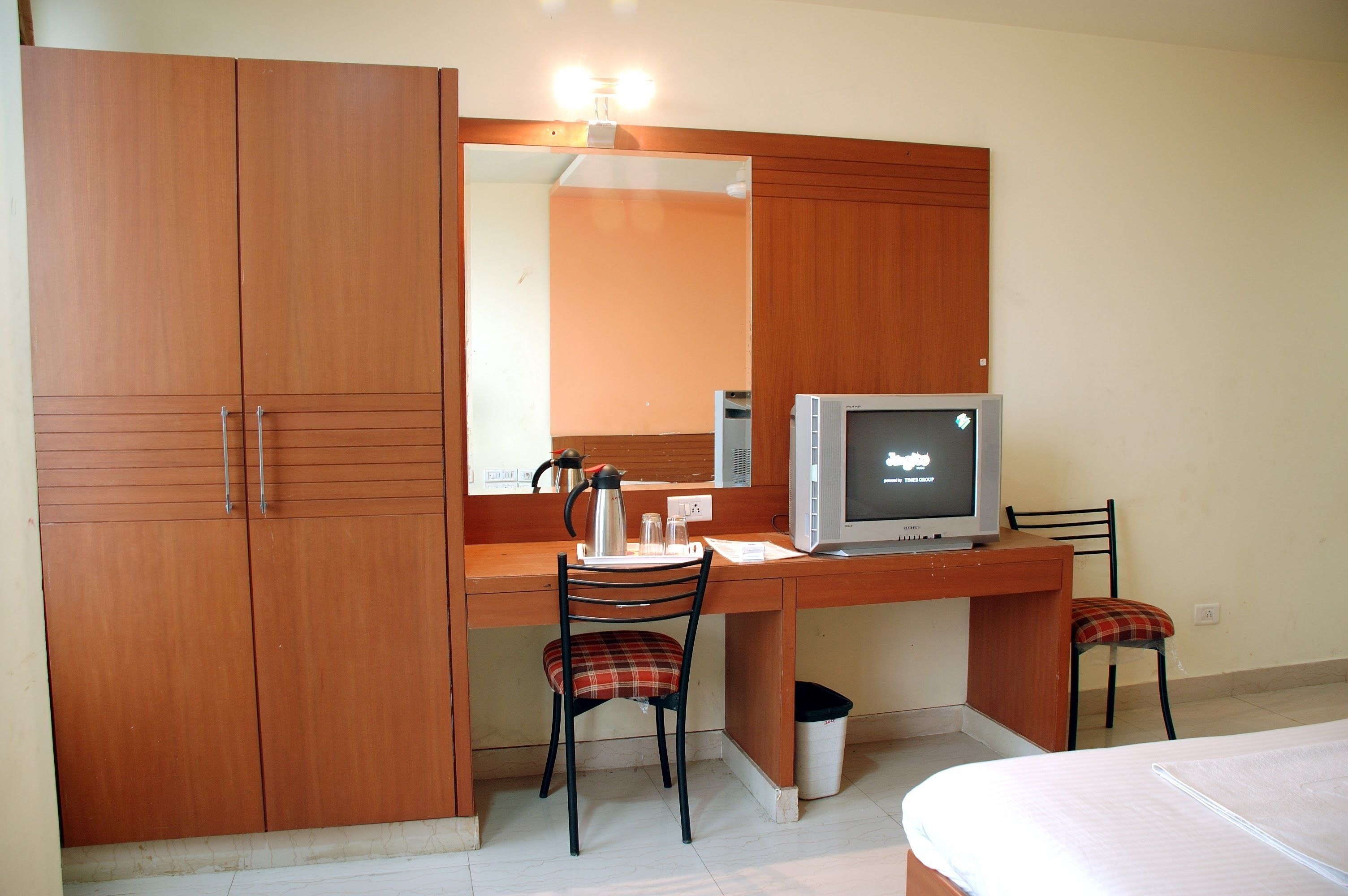 Une chambre à coucher comprenant un lit, un bureau avec une chaise, une télévision et une armoire.