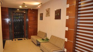 A lobby with a reception desk, two sofas, a decorative wall, and a door with a metal gate. - Hotel Imperial Classic (Hyderabad)