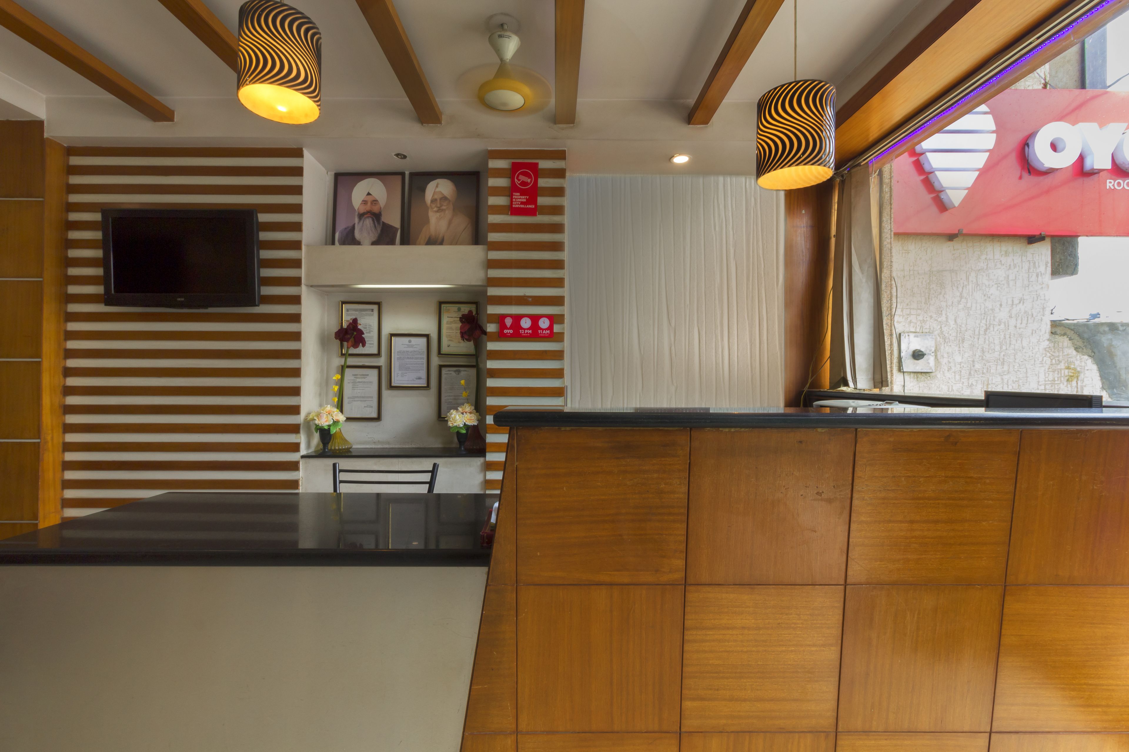 Un espace d’accueil avec un comptoir en bois, un téléviseur à écran plat fixé au mur, des certificats encadrés et un panneau rouge orné d’un symbole en forme de cœur.