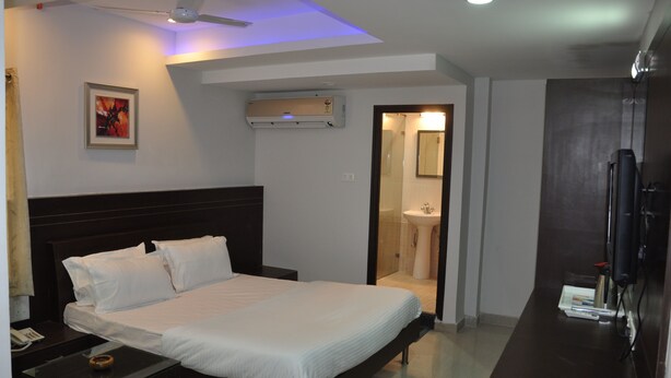 A hotel room with a bed, bedside table, and a TV. - Hotel Imperial Classic (Hyderabad)