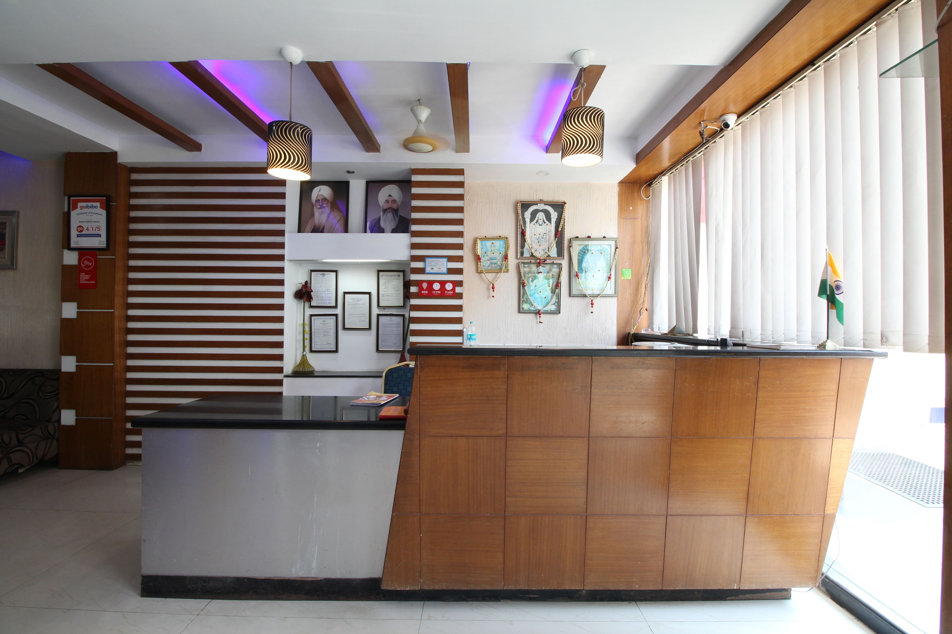 A reception desk with a wooden finish, framed pictures on the wall, and a ceiling with exposed beams and pendant lighting.