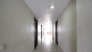 A long, narrow hallway with doors on both sides, leading to a bright area at the end. - Hotel Imperial Classic (Hyderabad)