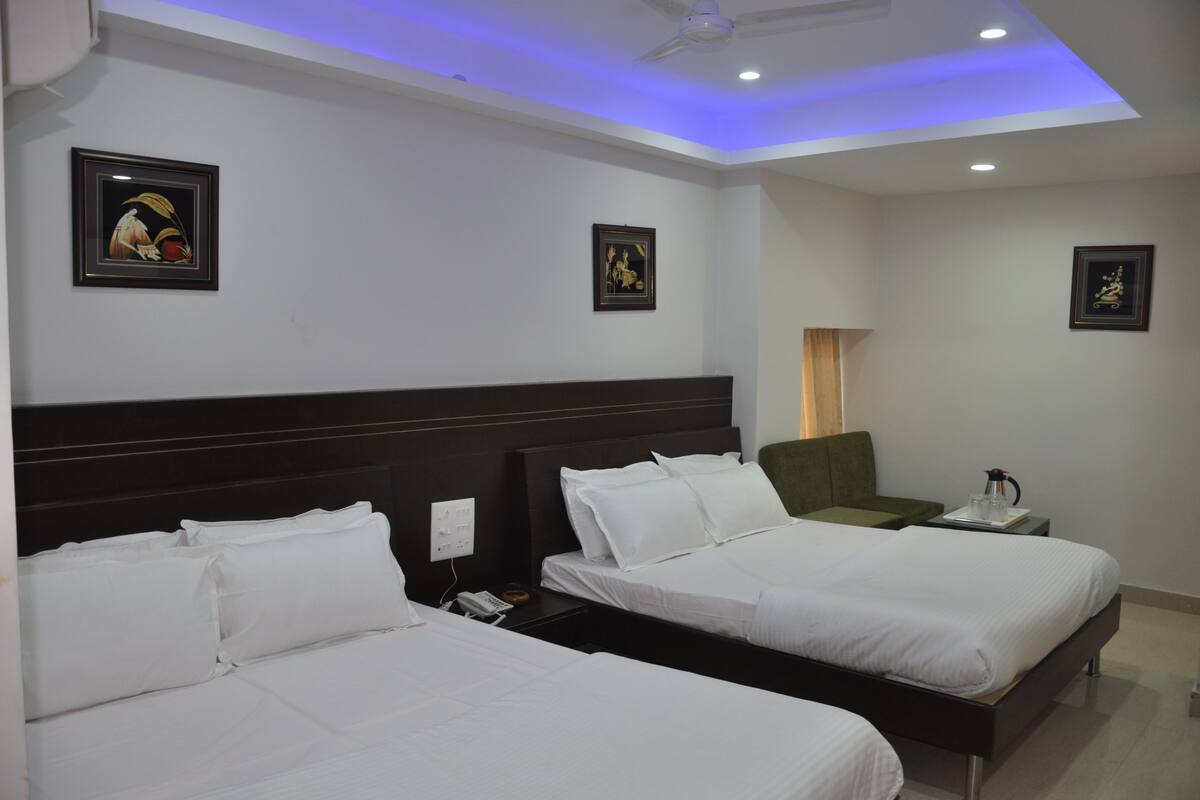 A hotel room with two beds, a nightstand with a phone and a lamp, and framed artwork on the walls.