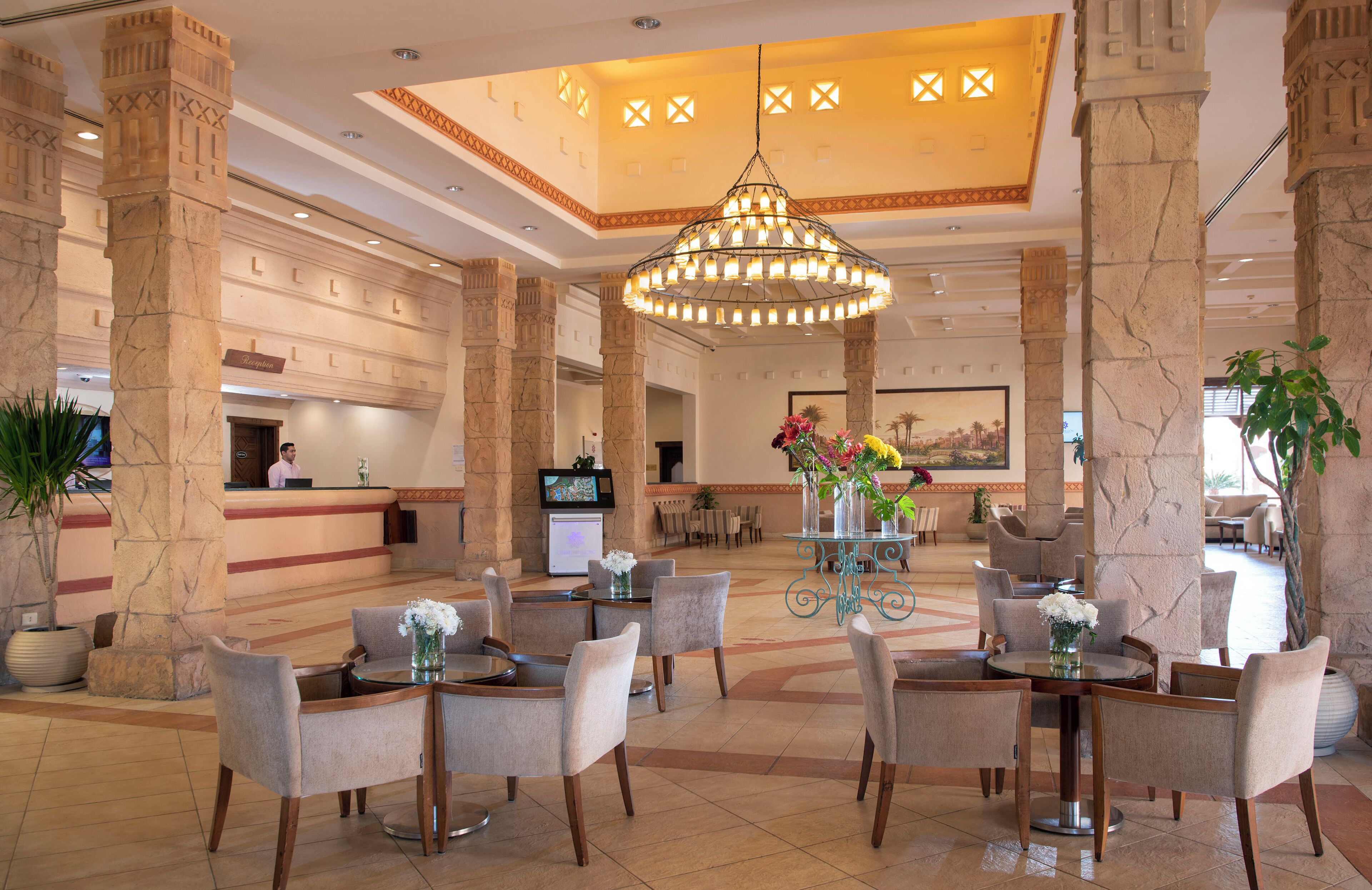 Un hall d’entrée orné de colonnes en marbre, d’un lustre et d’un comptoir d’accueil.