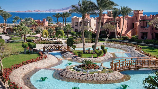 A resort with a large pool, palm trees, and a view of the sea. - Charmillion Sea Life Resort (Sharm El Sheikh)