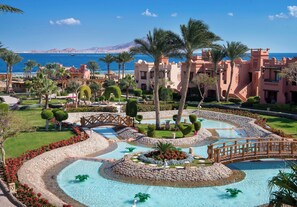 A resort with a large pool, palm trees, and a view of the sea. - Charmillion Sea Life Resort (Sharm El Sheikh)