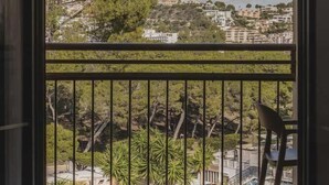 A balcony with a view of a cityscape, a chair, and a railing.
