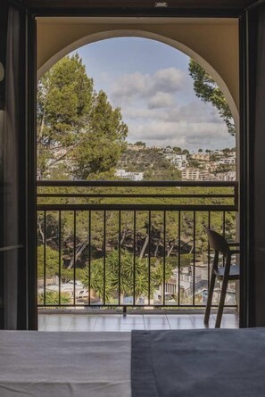 A balcony with a view of a cityscape, a chair, and a railing.