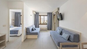 Een hotelkamer met een bed, een bank, een televisie en een raam.