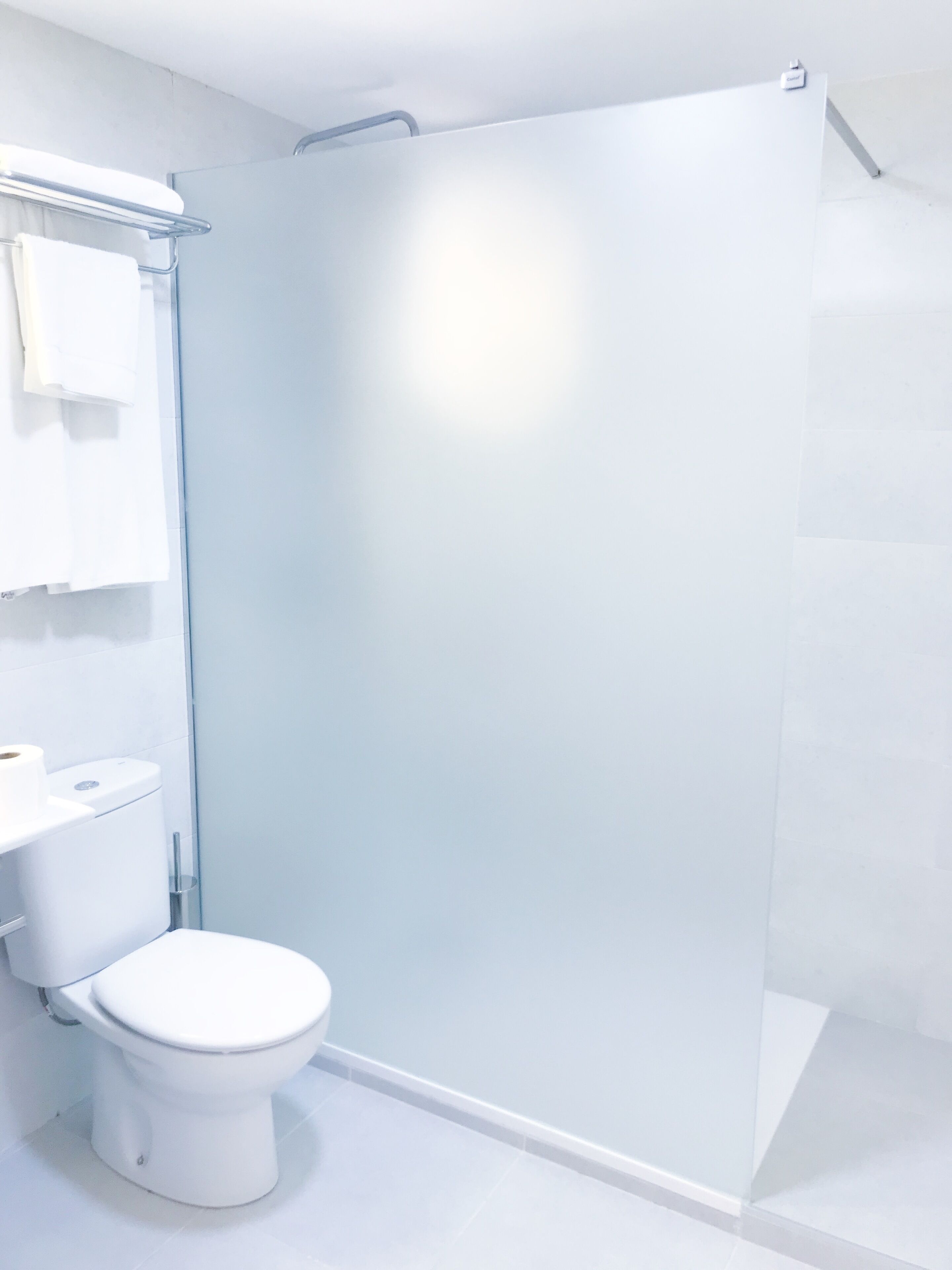 Un baño moderno con cabina de ducha de vidrio, inodoro blanco y lavabo.