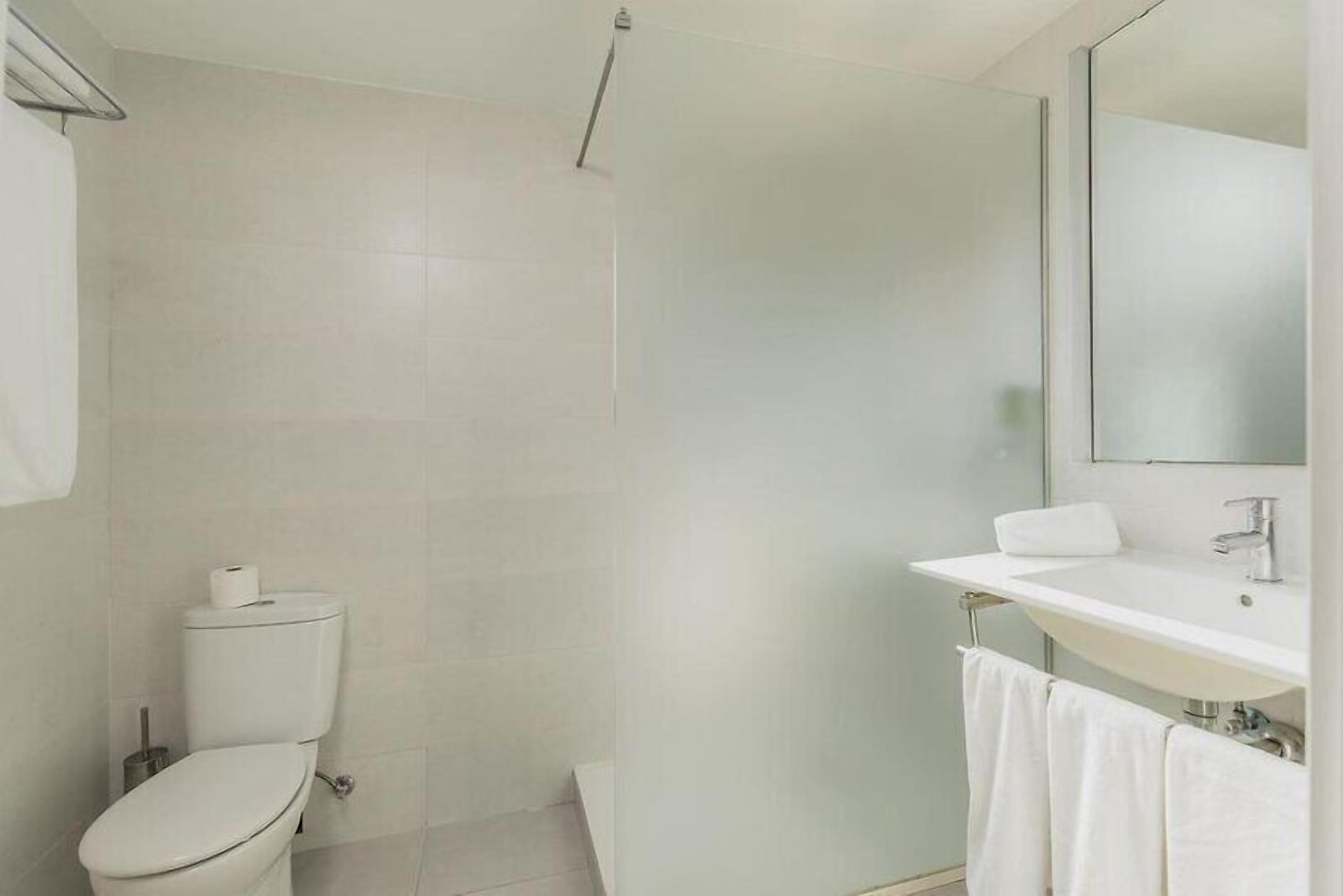 A modern bathroom with a toilet, sink, and mirror.