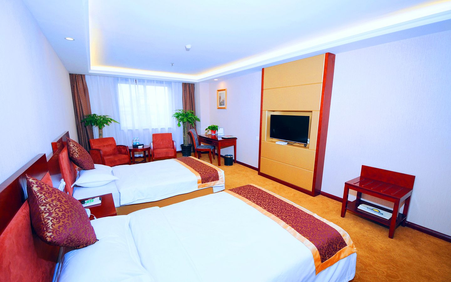A hotel room with two beds, a TV, a desk, and a chair.