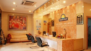 A reception area with a marble counter, black chairs, a painting, and a statue. - Days Inn By Wyndham City Centre Xian (Xi'an)
