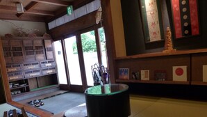 A traditional Japanese room with tatami flooring, a wooden bench, a low table with a green mat, and a sliding door leading outside. - Minshuku Kuwataniya (Takayama)
