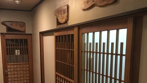 A hallway with traditional Japanese sliding doors, numbered room signs, and a wooden door with a grid pattern. - Minshuku Kuwataniya (Takayama)
