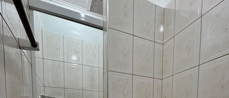 A bathroom with a toilet, a hand dryer, and a shower stall.